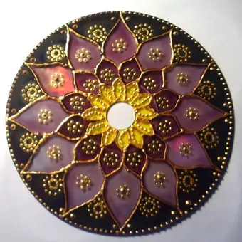 Upcycled CD hand-painted into a warm floral mandala, with hues of yellow and brown acrylics over a dark green background and emphasised with a golden acrylic.