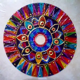 Upcycled CD hand-painted with a variety of colours, outlined and dotted with a golden acrylic into a vivid and striking mandala design