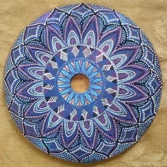 Upcycled CD intricately hand-painted into a geometric mandala using blue and purple gradients. White acrylic is used to emphasise this design with threaded lines and fine dots.