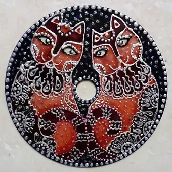 Upcycled CD beautifully hand-painted into two rusty-coloured cats over a dark green background. The intricacy of this design is emphasized by a silvery-white acrylic with the use of dots and lines.