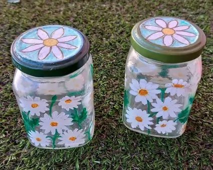 A pair of upcycled clear glass jars, hand-painted with lovely white daisies.