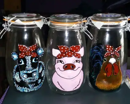 A set of three upcycled clear mason jars, displaying different cute cartoon farmyard animals.