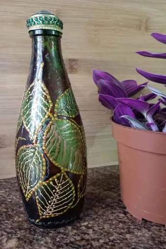 A gorgeous upcycled green glass bottle, hand-painted with ornamental leaves with a golden texture.