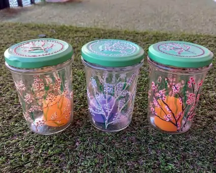 A trio of upcycled clear glass jars, hand-painted with complimentary coloured blossoms.