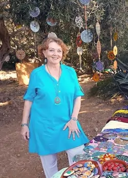 Vera at the market fair. Displaying cds hanging from the tree branches and a table with other products.