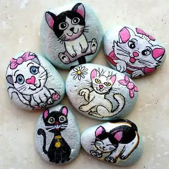 Six hand-painted pebbles, depicting various cartoon cats in different styles.