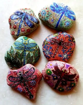 A set of hand-painted pebbles, depicting colourful dragonflies with intricate designs.